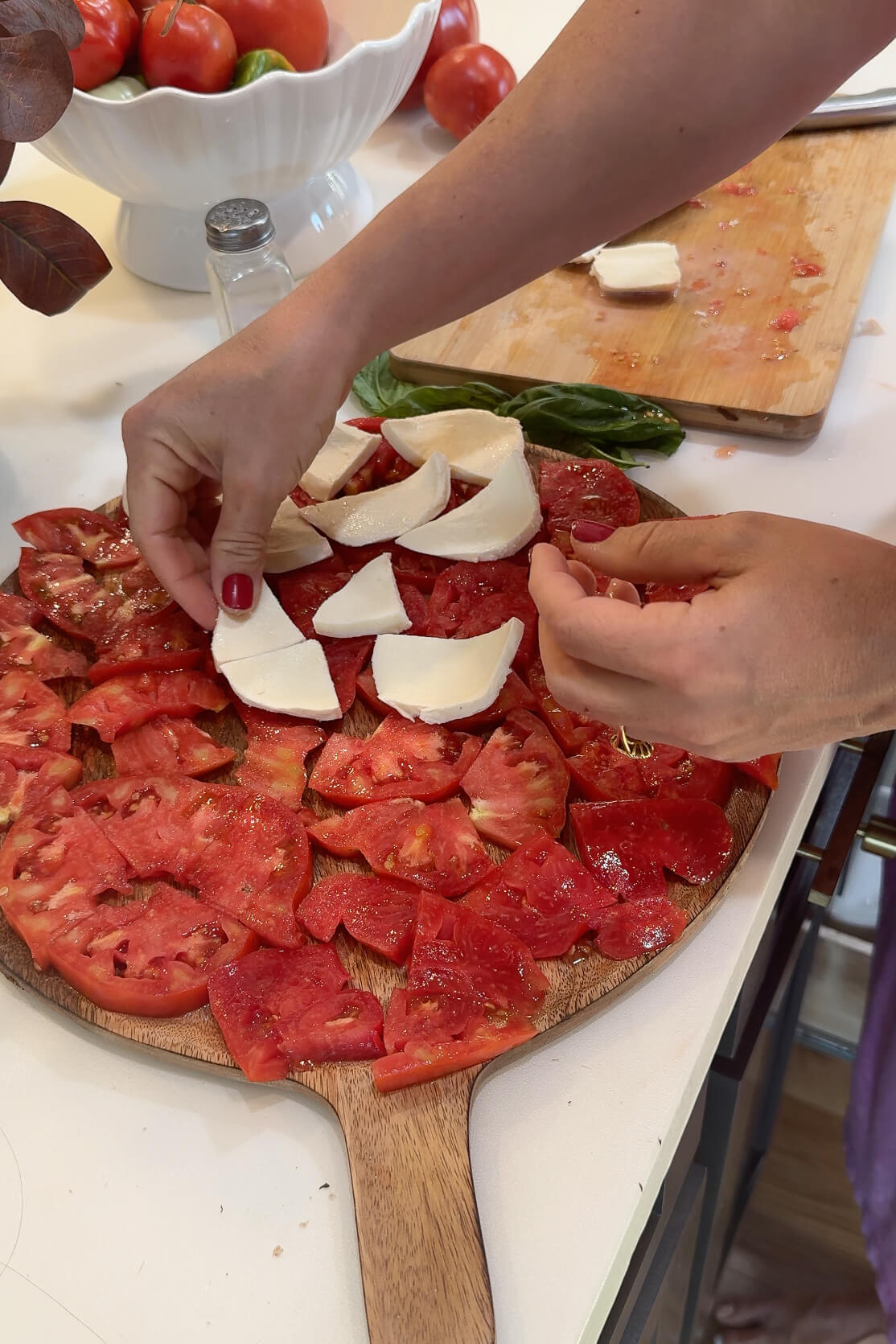 Layering fresh mozzarella cheese on tomatoes for caprese salad.